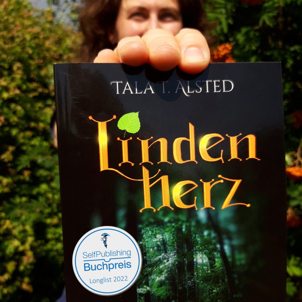 Tala T. Alsted hält ihr Buch "Lindenherz - 824 Jahre durch die Zeit" mit Batch "Nominiert für den Selfpublishing Buchpreis 2022" in die Kamera