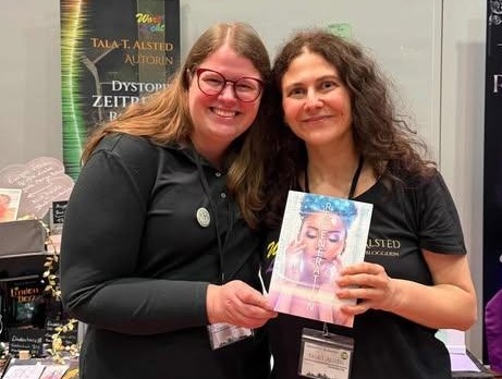 Zwei Frauen nebeneinander auf der Buchmesse - Tala T. Alsted hält ihr Buch "RE-GENERATION"