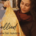 Aitorin Tala T. Alsted hält ein goldenes Glitzertuch über ein noch verborgenes Buch