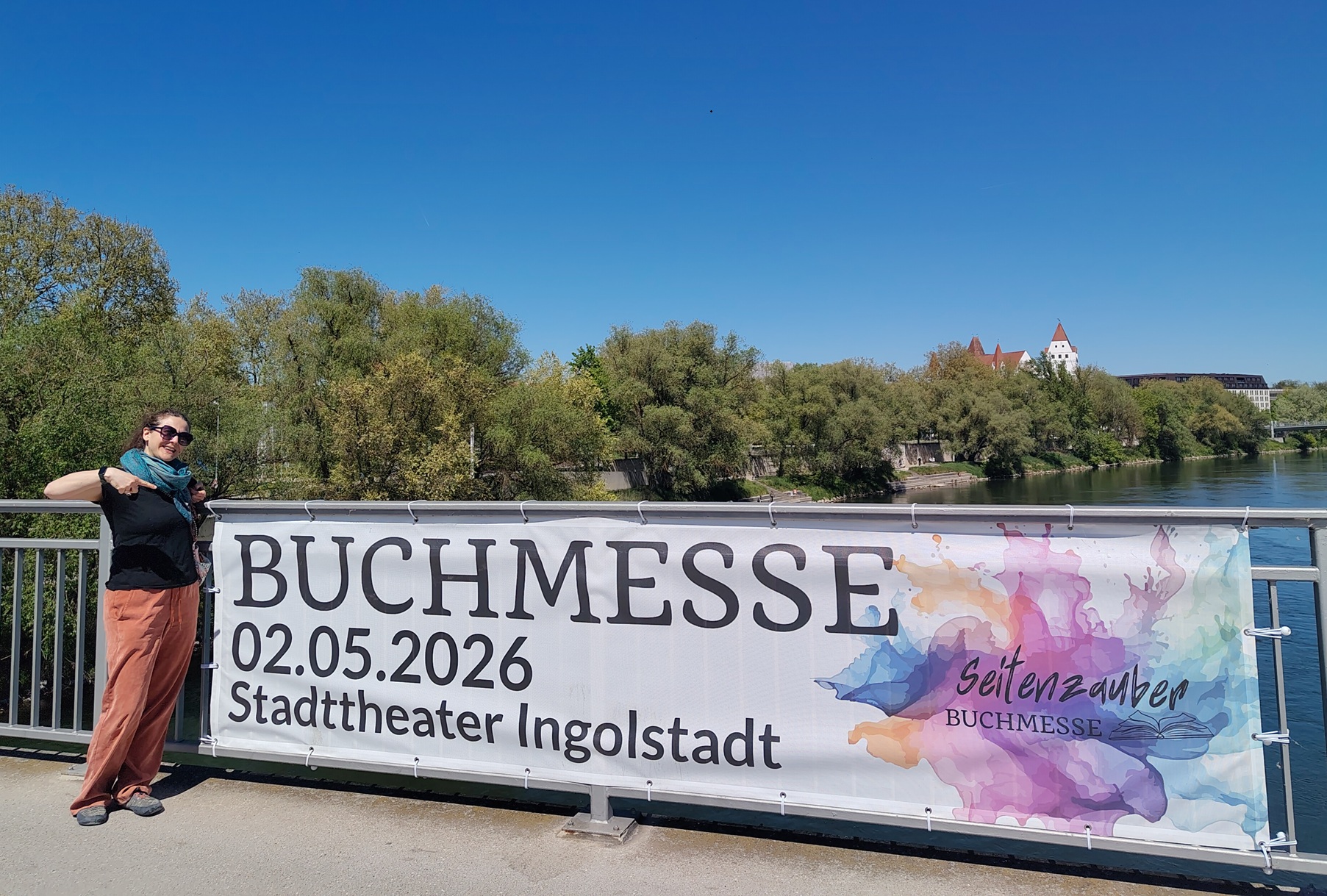 Autorin Tala T. Alsted vor Banner der Seitenzauber-Buchmesse 2026 in Ingolstadt auf einer Brücke