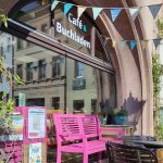 Schaufenster mit bunten Wimpeln und einer pinkfarbenen Bank davor