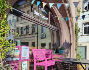 Schaufenster mit bunten Wimpeln und einer pinkfarbenen Bank davor